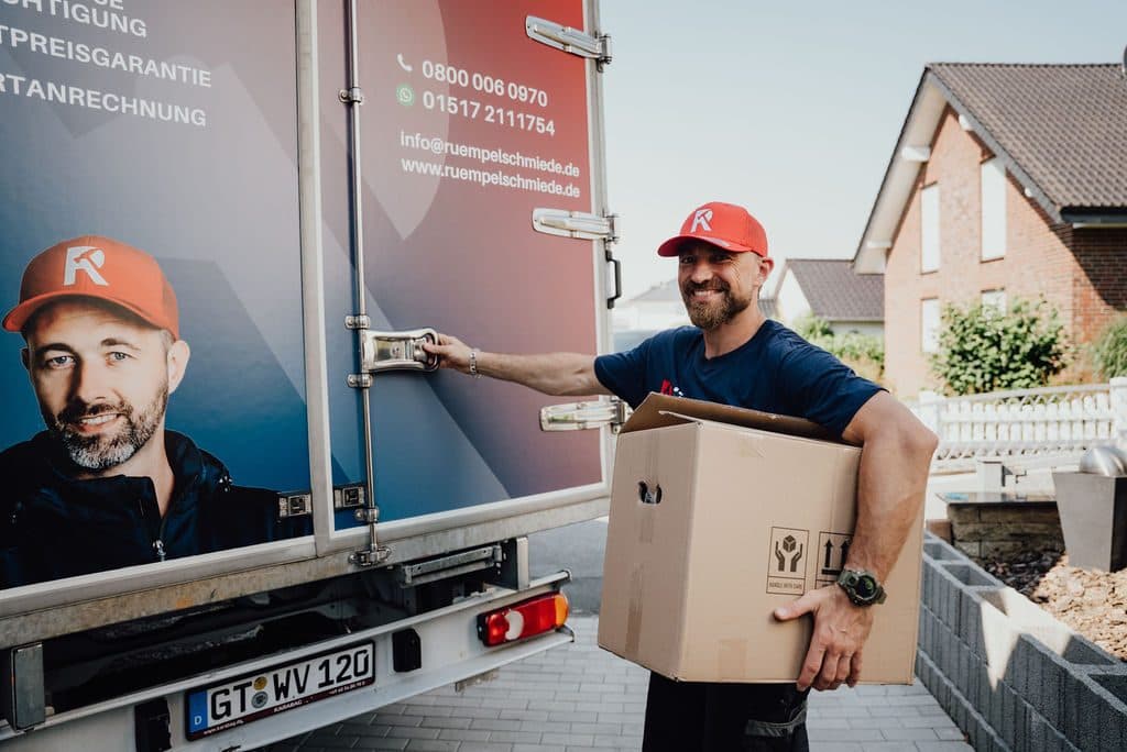 Mitarbeiter trägt Kartons vom Transporter