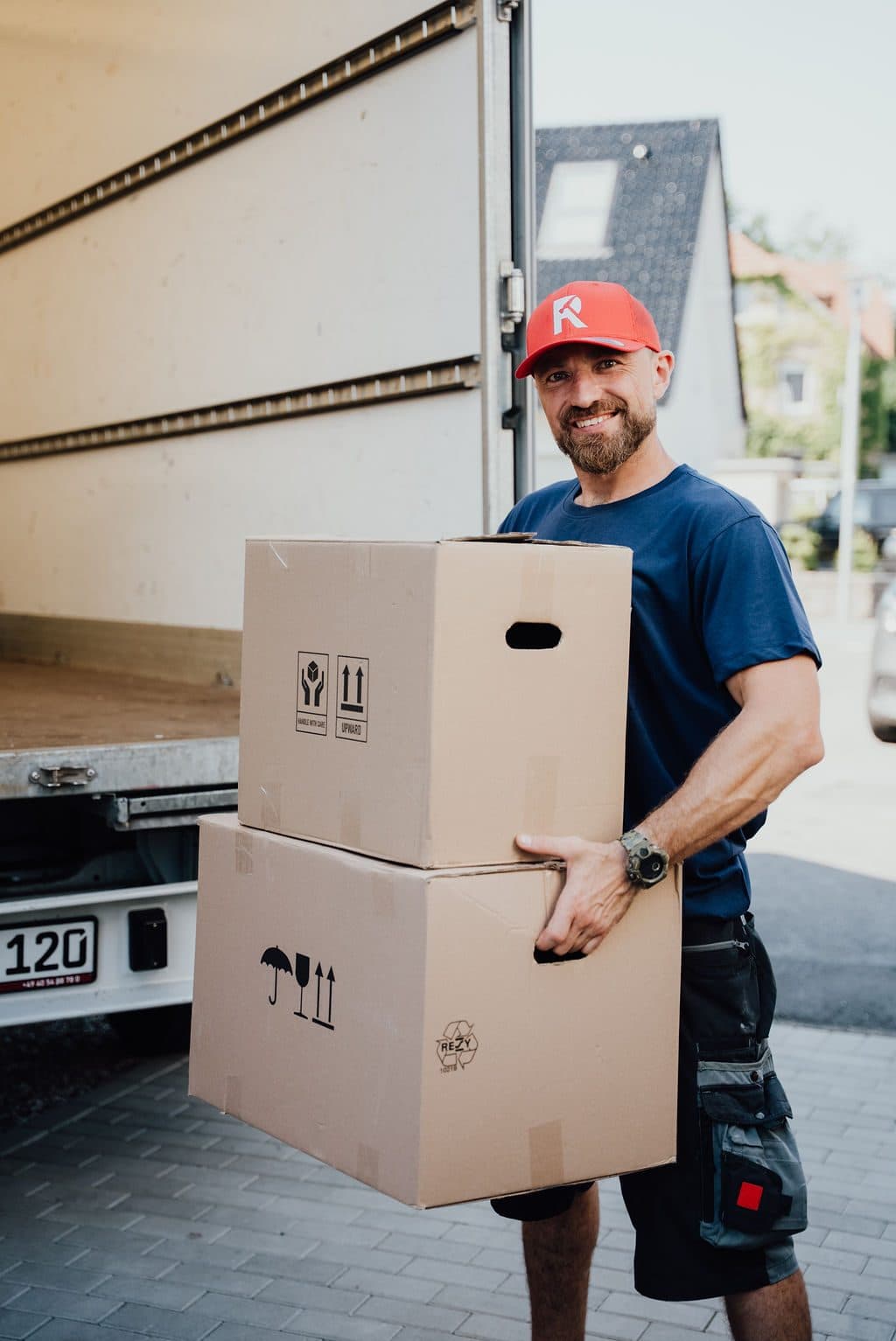Mitarbeiter trägt Kartons zum Transporter