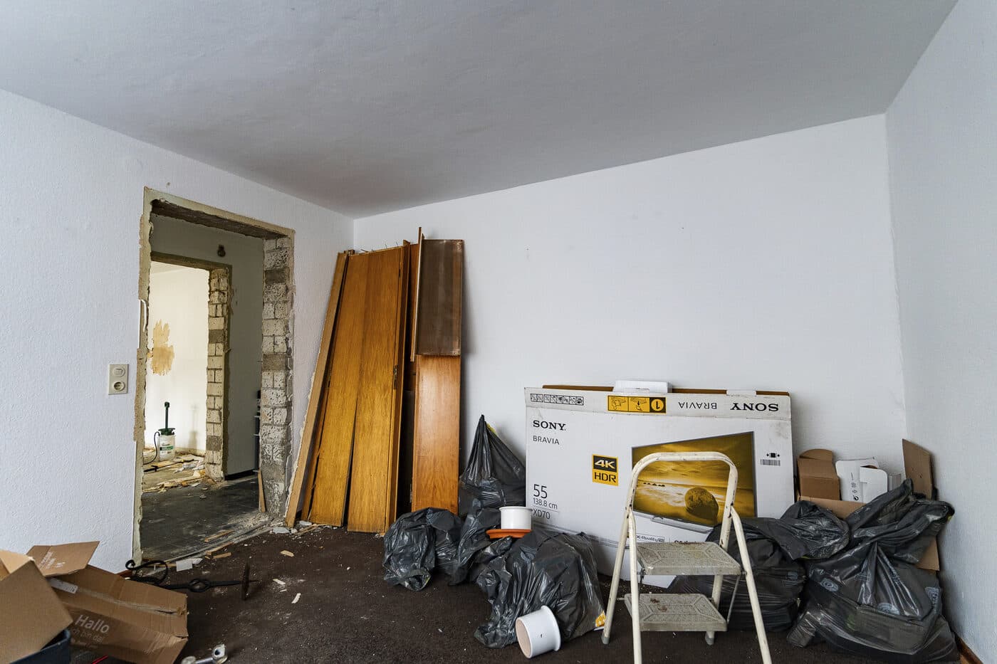 Wohnzimmer mit Möbelresten und Müllsäcken vor der Entrümpelung